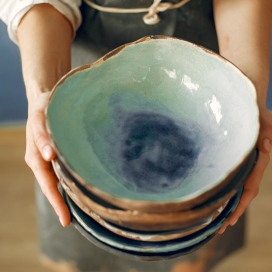 A young woman holds a ceramics dish in her hands